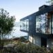 charred cedar and glass cabin on hill facing water