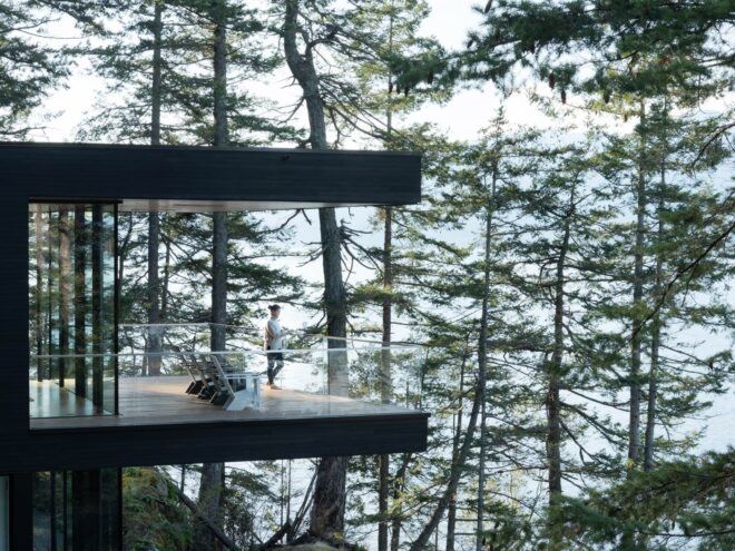 person on patio with glass rails facing water