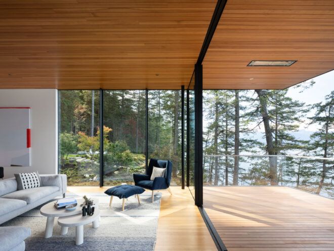 blue chair and foot rest near two glass walls leading to wood balcony