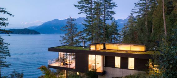 cedar and glass cabin with green roof facing water