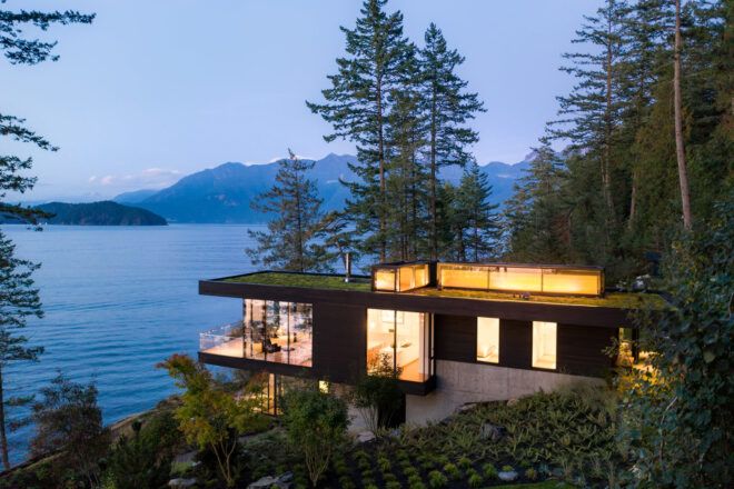 cedar and glass cabin with green roof facing water