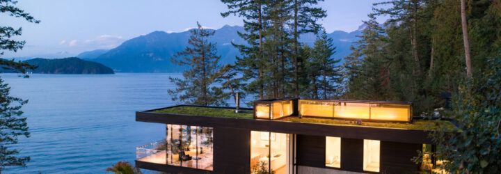 cedar and glass cabin with green roof facing water