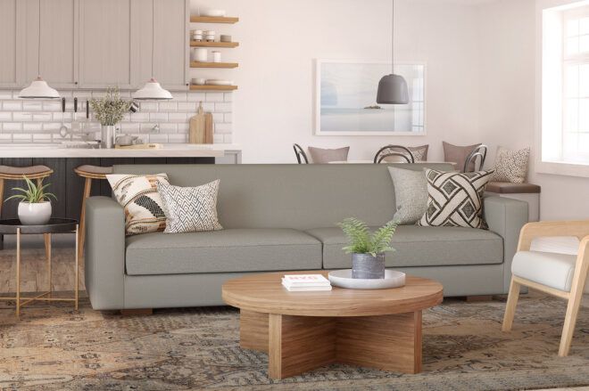 A gray sofa and round wood coffee table in a living room.