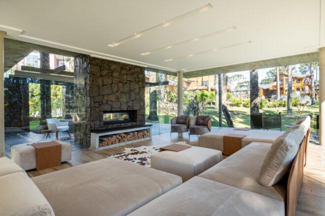 stone fireplace with logs underneath facing a beige sofa