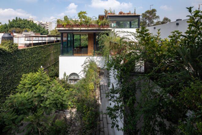 A corporate building with a white and glass facade. Lush greenery surrounds the building.