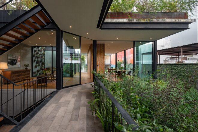 An indoor/outdoor area where an outdoor walkway near greenery connects to an indoor office area with stairs.