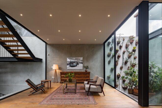 An indoor sitting area with a patterned red and cream colored rug, gray sofa, coffee table, chairs and wood cabinets.