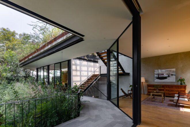An indoor/outdoor area where an outdoor walkway near greenery connects to an indoor office area with stairs.
