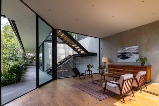 An indoor/outdoor area where an outdoor walkway near greenery connects to an indoor office area with stairs.