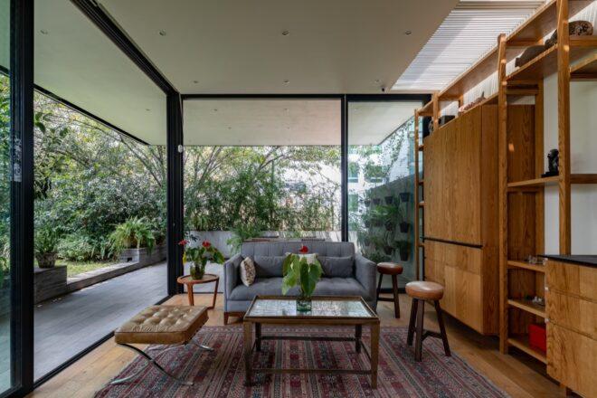 An idoor sitting area with a patterned red and cream colored rug, gray sofa, coffee table, chairs and wood cabinets.