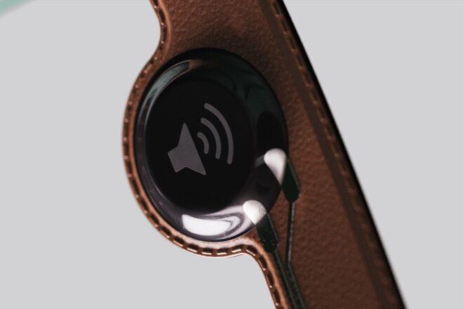 A brown leather strap with a black speaker attached.