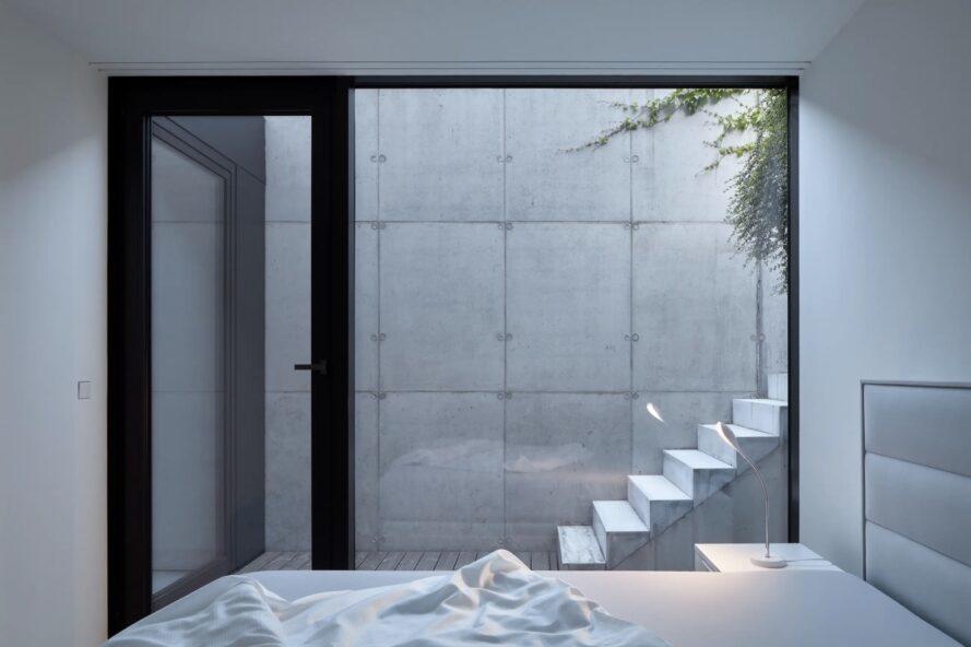 white bedroom with glass wall revealing set of outdoor steps