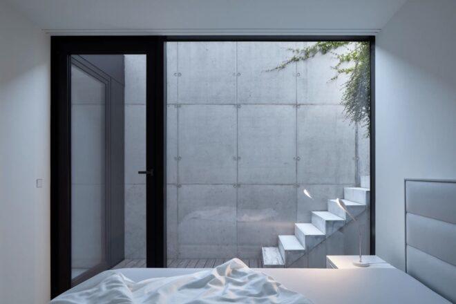 white bedroom with glass wall revealing set of outdoor steps