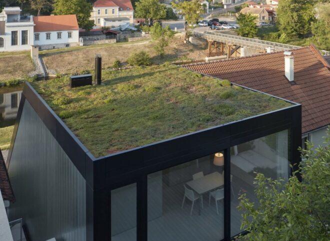 black metal-framed home with green roof