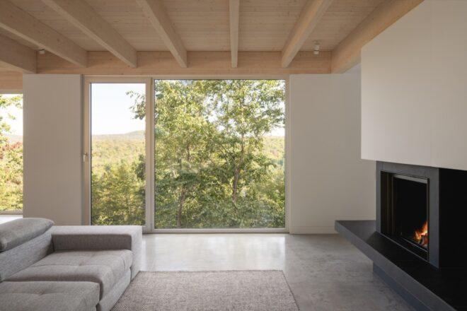white couch facing fireplace near glass wall