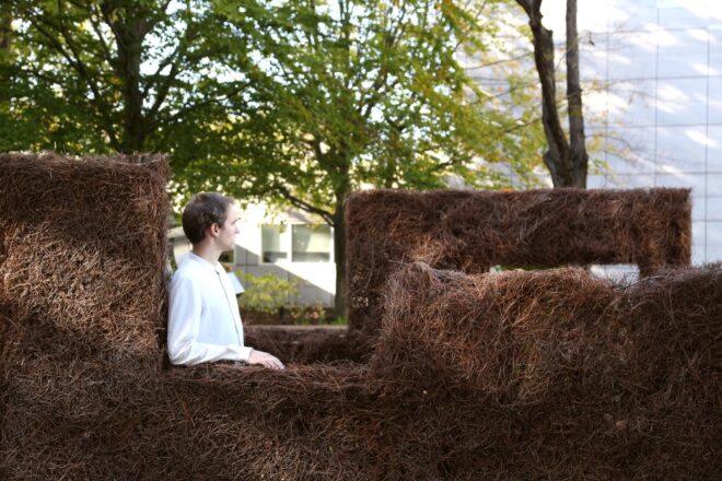 person leaning on wall made of plants