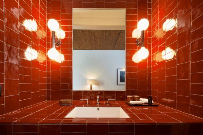 bathroom with large mirror and red tiles