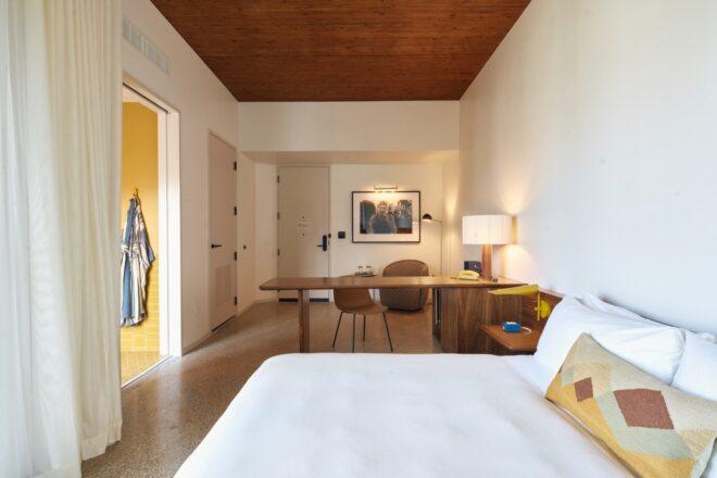 white hotel room with orange accents and a wood desk