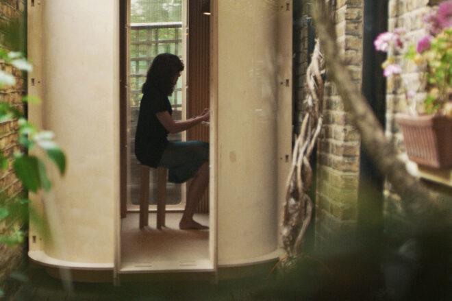 A person working inside a pod room, as viewed through the room's front door.