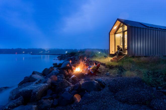 A night view of a gabled home on a rocky cliff.