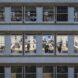 exterior of office building with windows revealing people working at desks inside