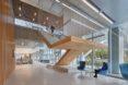 A wood staircase in the middle a white hallway area.