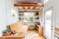 tiny home living room with orange velvet sofa and wood shelves