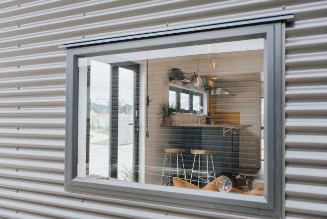 window of black tiny home revealing minimalist interiors