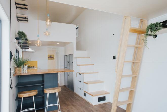wood ladder across from white staircase in tiny home
