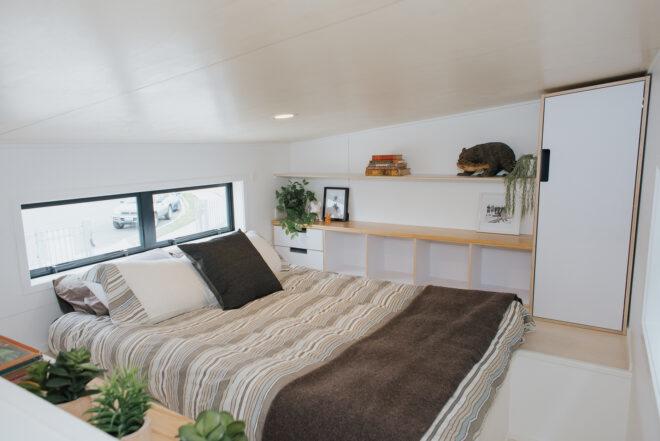 queen bed with brown bedding in a lofted space