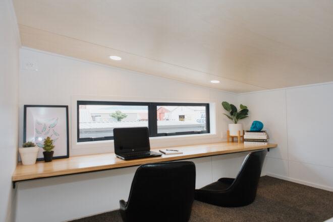 long wood desk with two office chairs in a loft