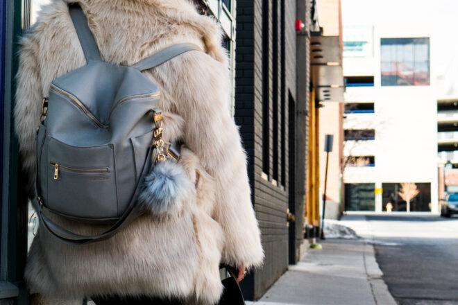 person wearing fur coat and backpack with fur keychain