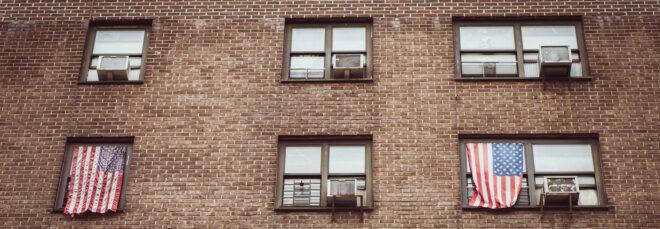 american flags hanging from windows next to air conditioners
