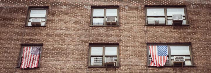 american flags hanging from windows next to air conditioners