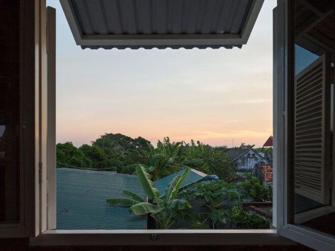 window open to reveal sunset over trees