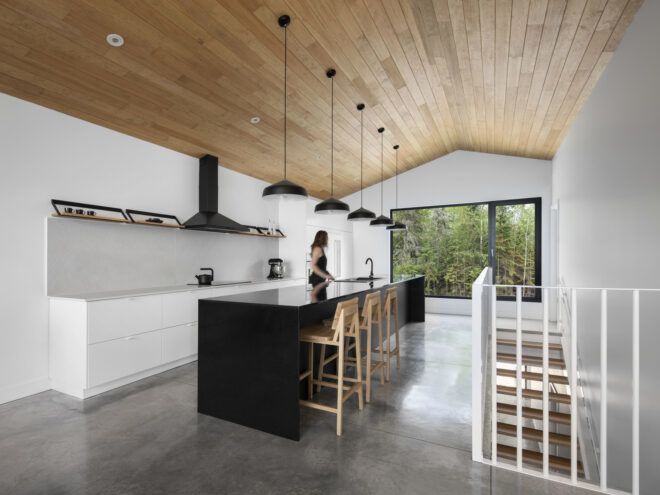 white room with wood ceiling and black island in the kitchen