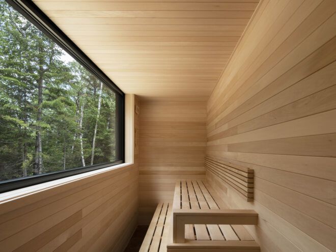 wood-lined sauna with large window overlooking a forest