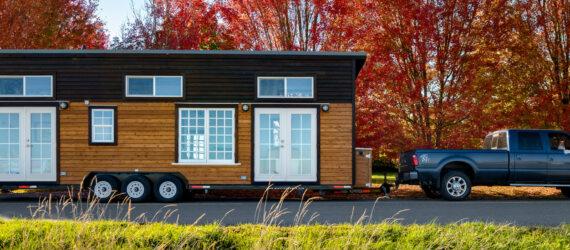 truck pulling tiny home with wood cladding