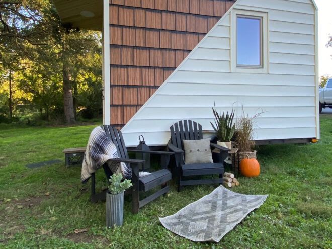 two black patio chairs outside a white and wood tiny home