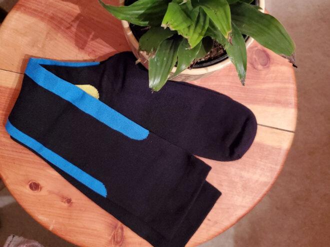 black, blue and yellow compression socks on wood table near plant