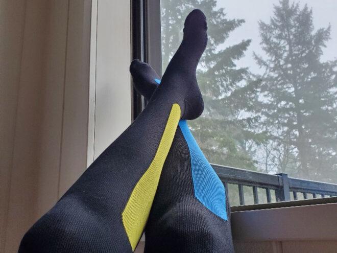 person wearing compression socks with feet resting against window