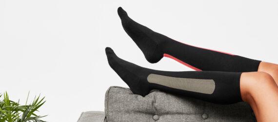 person lying on gray sofa and wearing compression socks