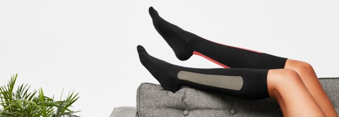 person lying on gray sofa and wearing compression socks