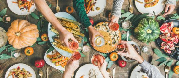 people toasting with drinks over a table of plant-based dishes