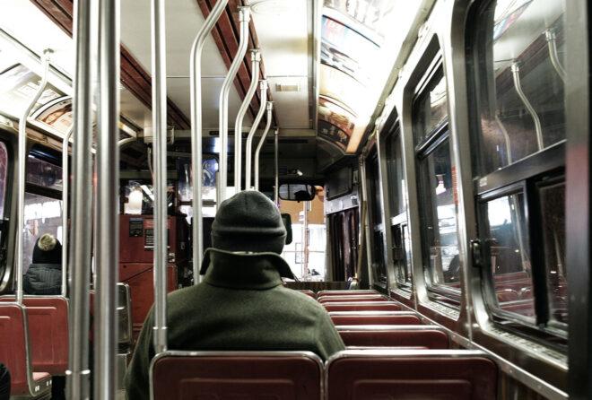 person bundled up in a coat and riding the subway