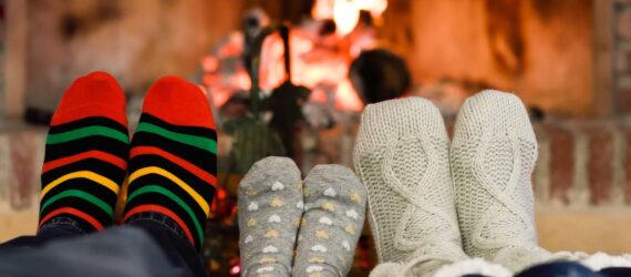 people in cozy socks with feet near fireplace