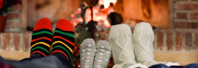 people in cozy socks with feet near fireplace