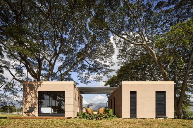Two square volumes connected by a pergola. Large trees grow over the home.