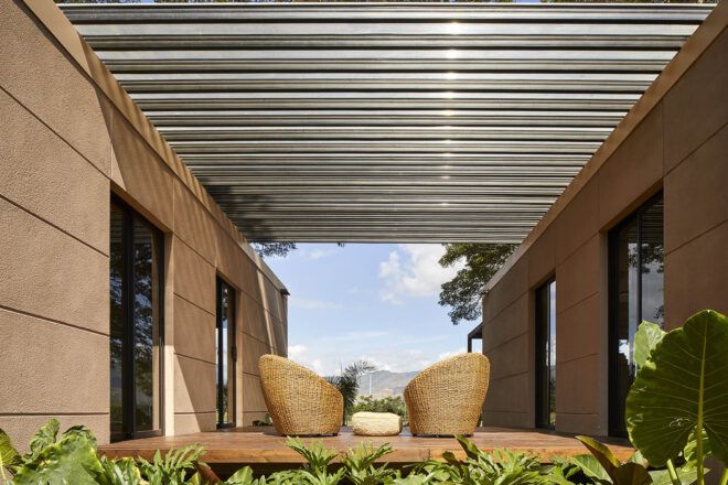 An outdoor sitting area with chairs covered by a pergola.