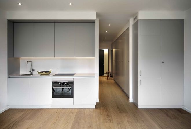 A bright, empty kitchen area with white cabinets.